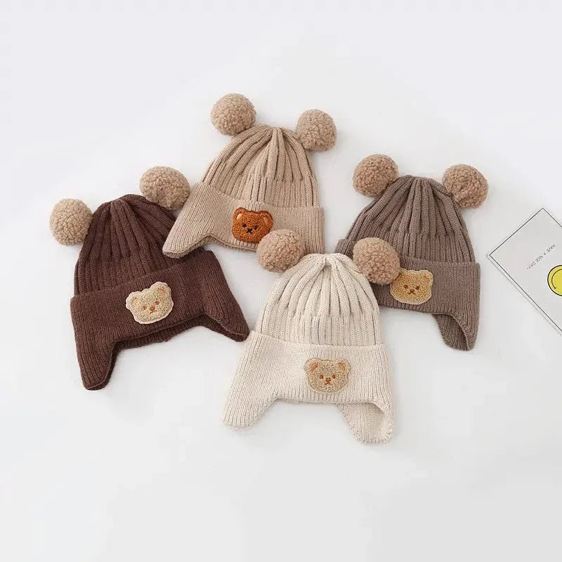 Baby wintermutsen bruin beige beer pompons collectie plat uitgelegd